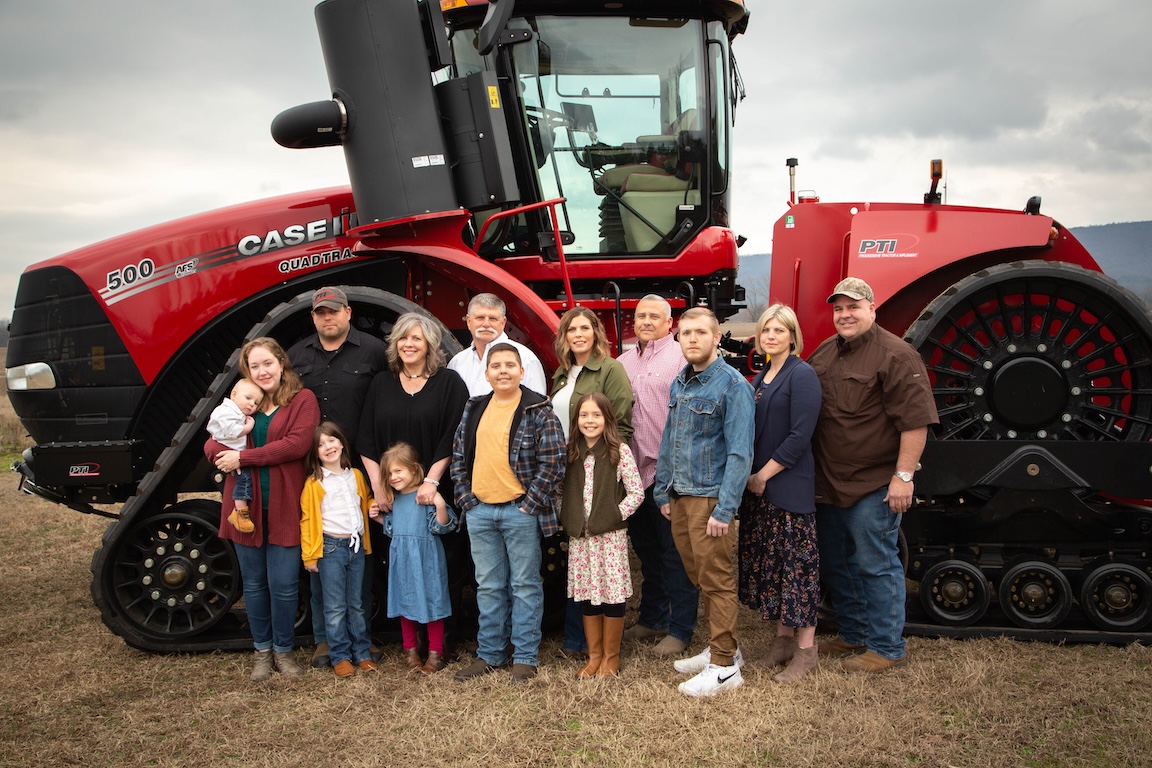 The Ralston family in front of farm equipment