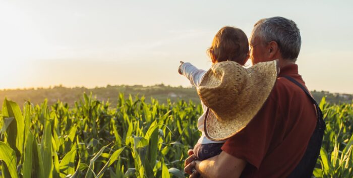 Man holding a child looking out on a farm field